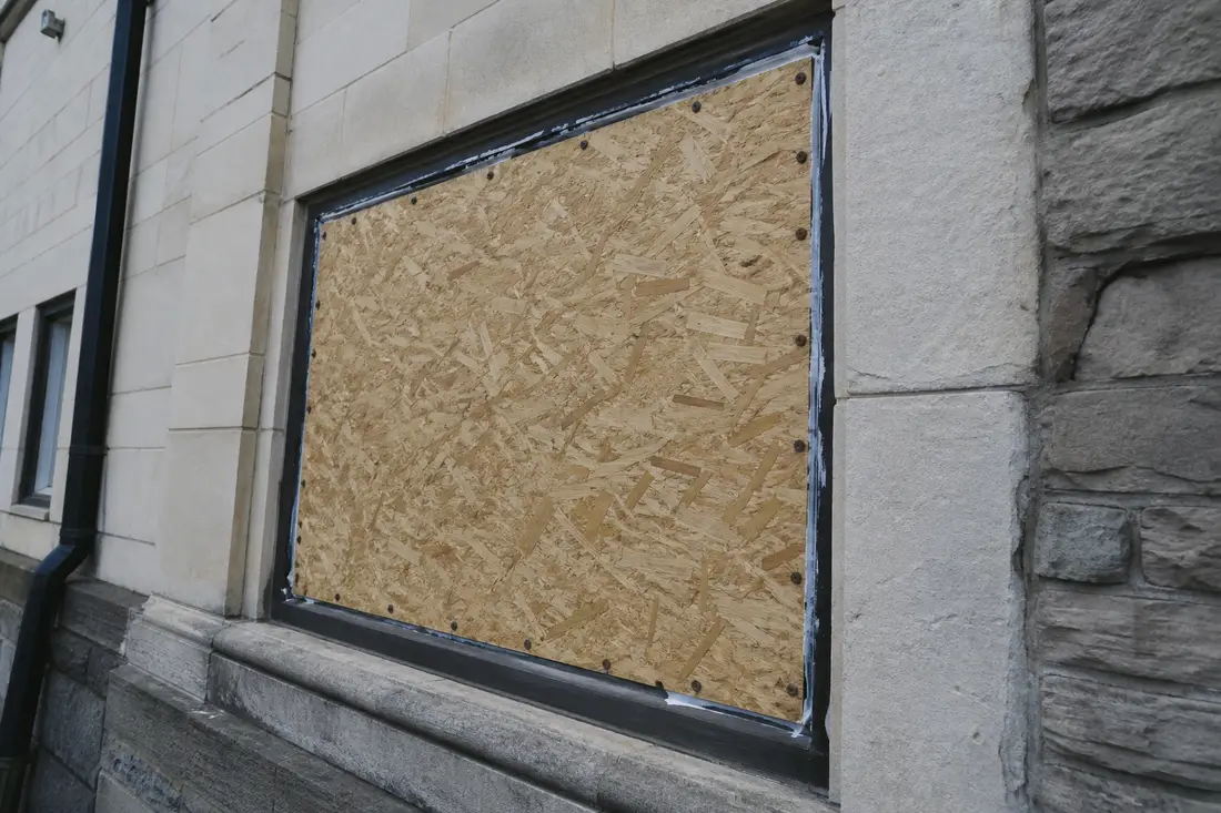 Panneau de contreplaqué vissé sur le cadre d'une fenêtre brisée pour une fermeture provisoire sécurisée
